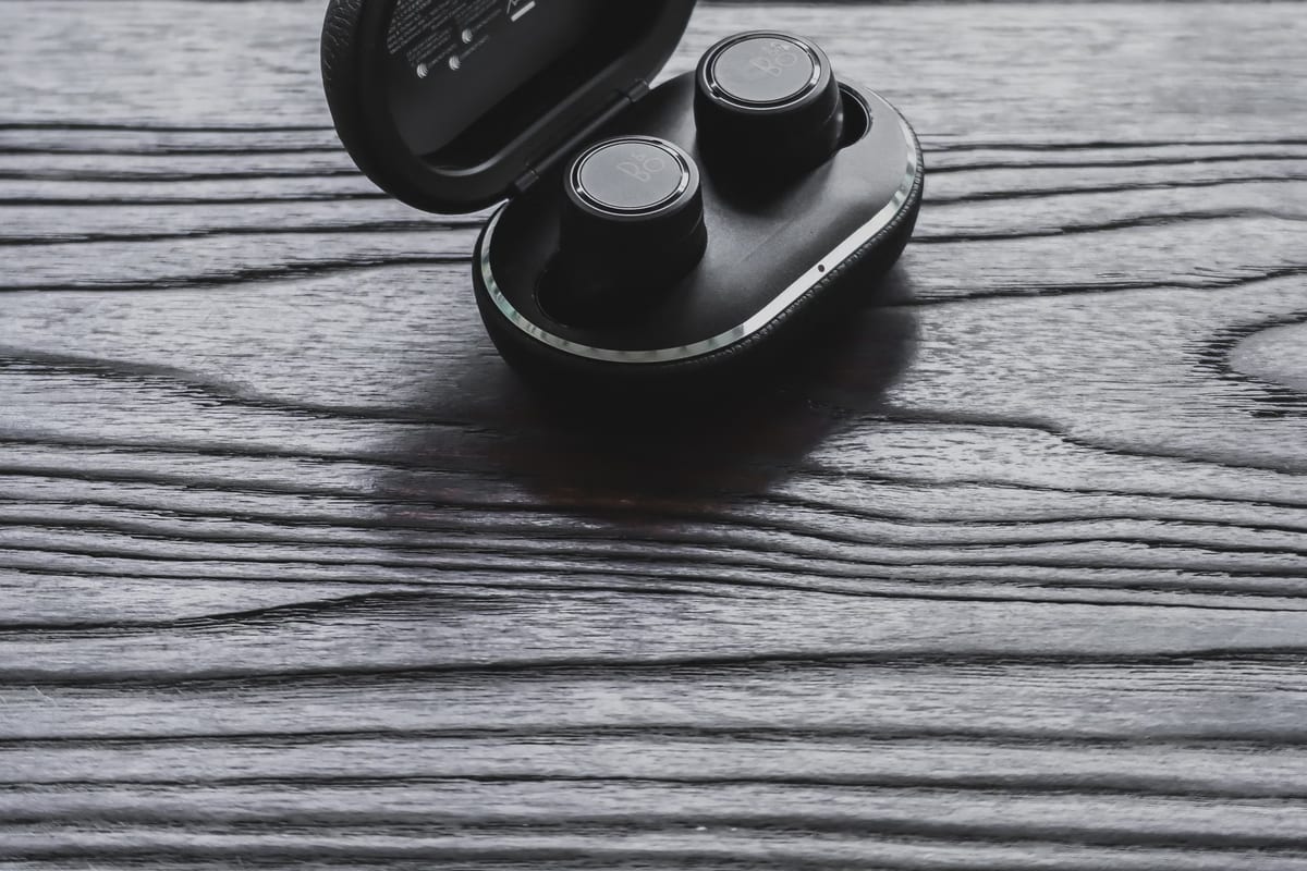 Wireless earbuds in their open charging case on the audio bench